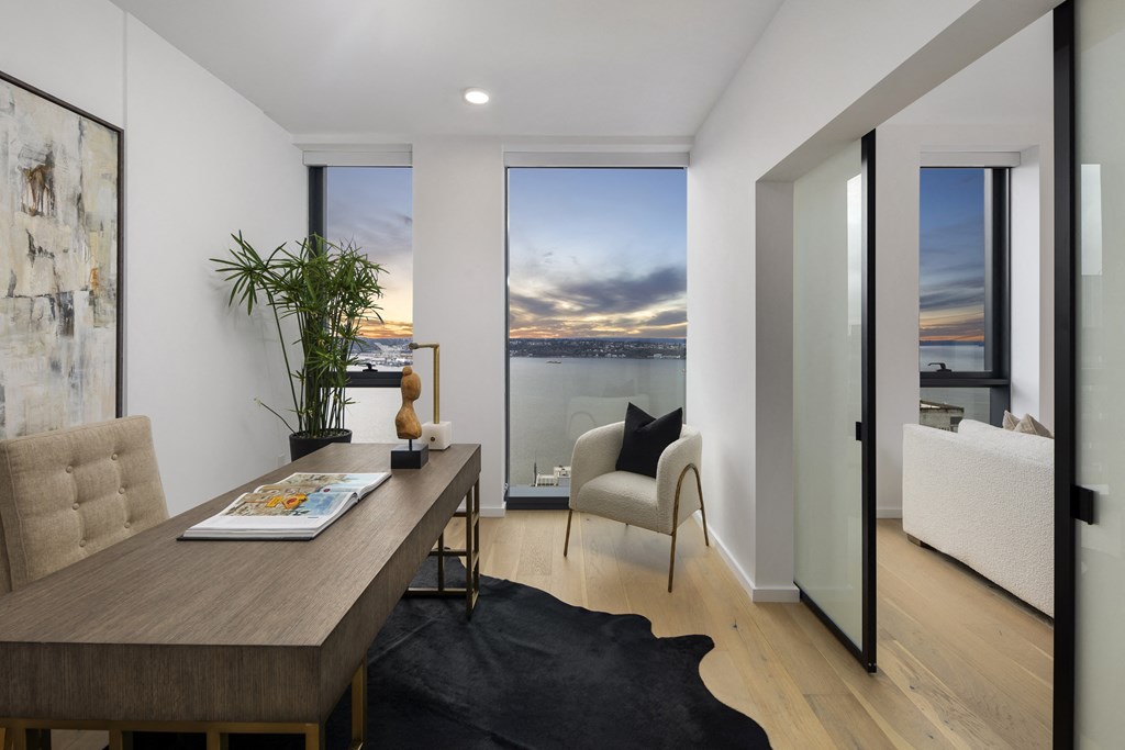 a home office with a desk and a view of the water and a couch