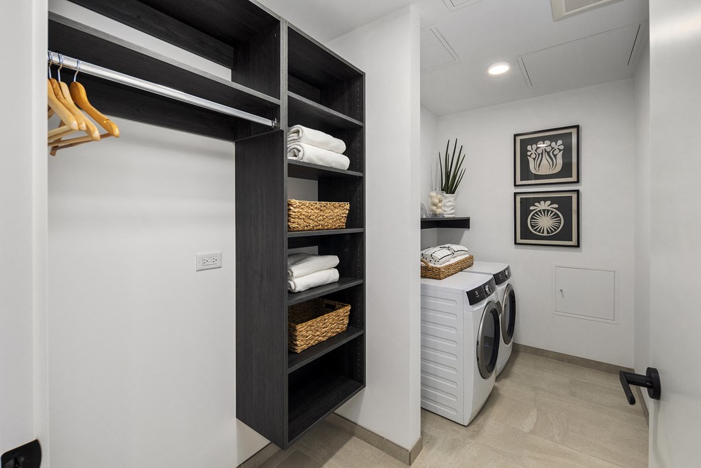 a laundry room with a white washer and dryer and a black closet