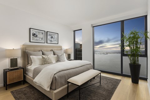 a bedroom with a bed and a large window overlooking a body of water