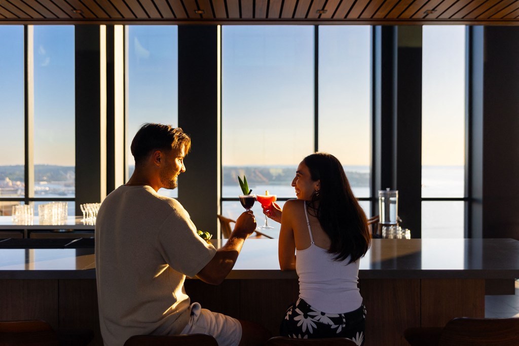 a man and a woman sitting at a bar with a drink