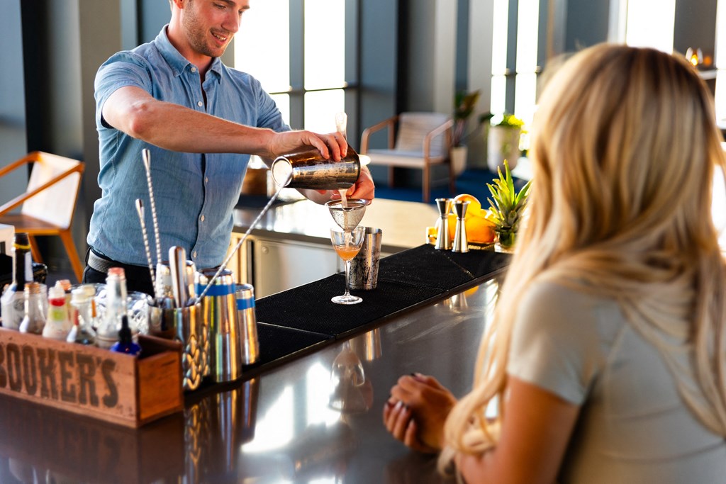 a bartender pouring a drink for a woman at a bar
