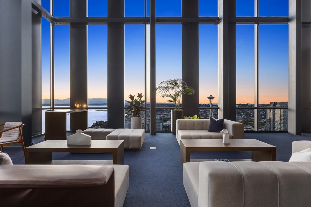 a lounge area with couches and coffee tables and floor to ceiling windows with a view of
