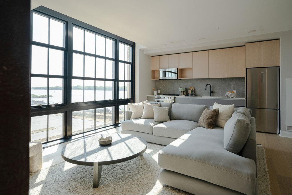 a living room with a large white couch and a coffee table in front of a large window