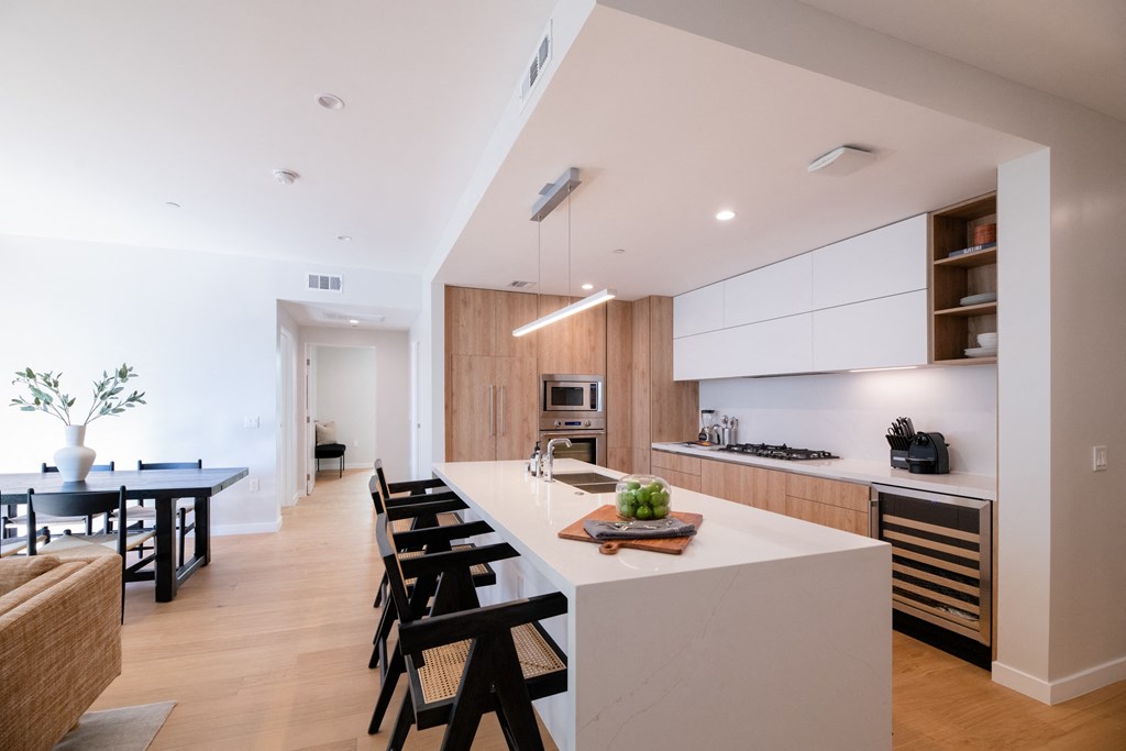 a kitchen with a large white island with a sink and a bunch of black chairs
