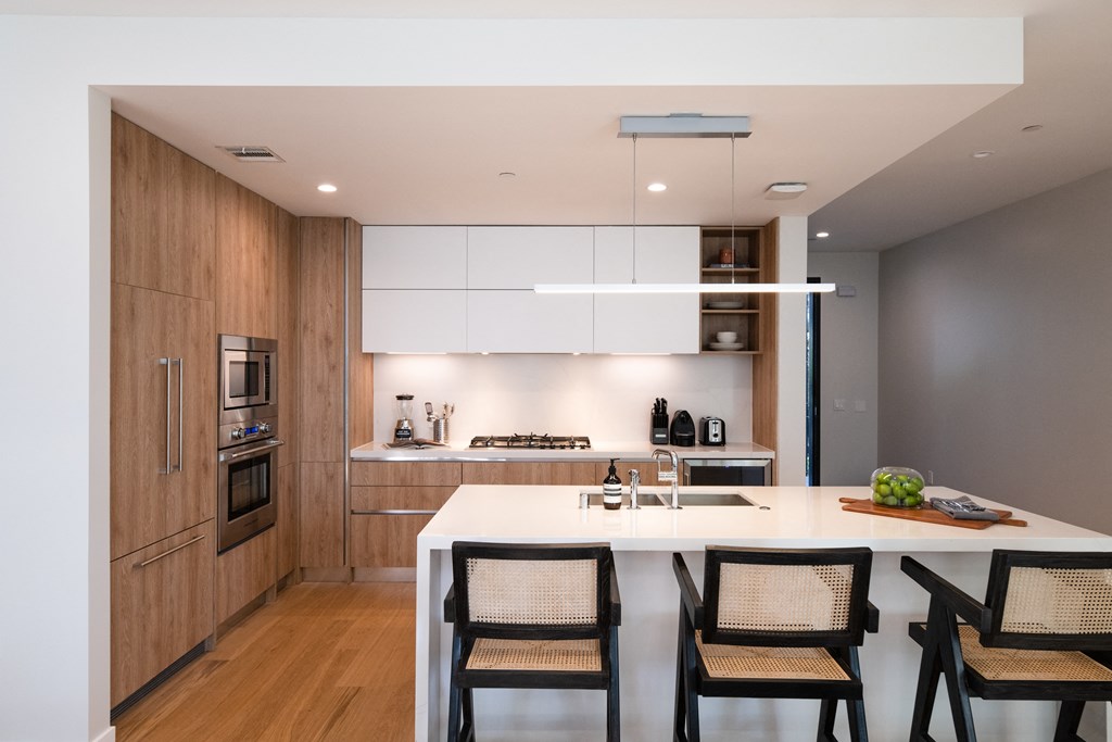 a kitchen with a large white island with a white countertop and four black chairs