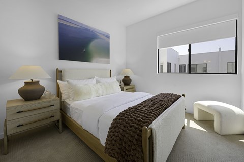 A bedroom with a large bed, a nightstand with a lamp, and a painting on the wall.