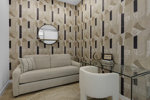 A living room with a beige couch, a glass table, and a white chair.