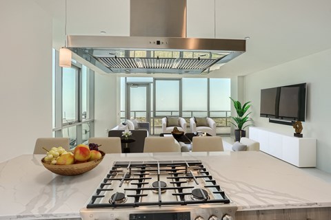 a kitchen and living room with a stove and a bowl of fruit