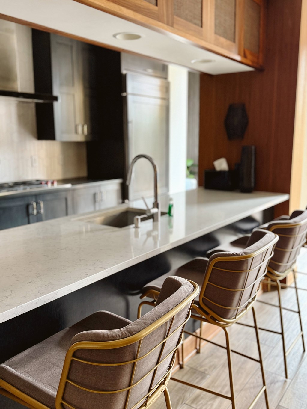 A kitchen with a long counter and chairs.