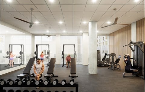 A gym with people working out and a woman on a rowing machine.