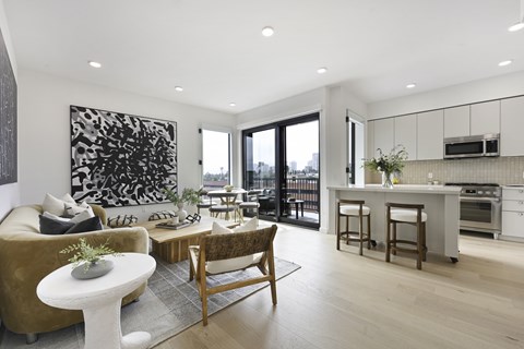 A modern living room with a brown sofa, a white coffee table, and a large abstract painting on the wall.