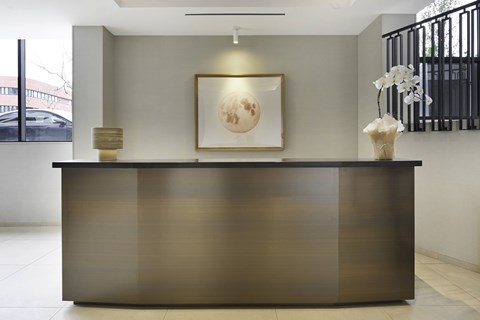 A reception desk with a framed picture on the wall above it. The Ten310 Lobby