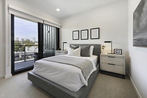 A bedroom with a large bed, a nightstand, and a view of the city.