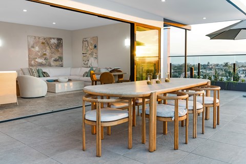 A modern rooftop dining room with a large table and chairs. overlooking the Los Angeles skyline