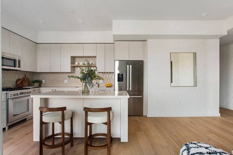 A kitchen with a white island and two chairs.