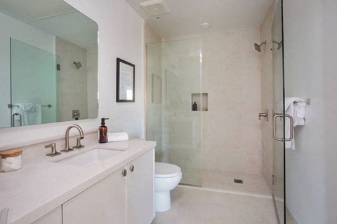 A white bathroom with a glass shower stall and a toilet.
