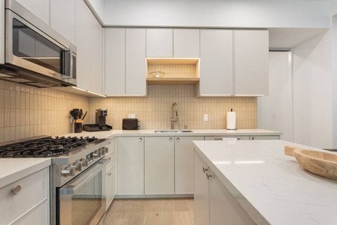 A modern kitchen with white cabinets and a stainless steel stove top at Ten310