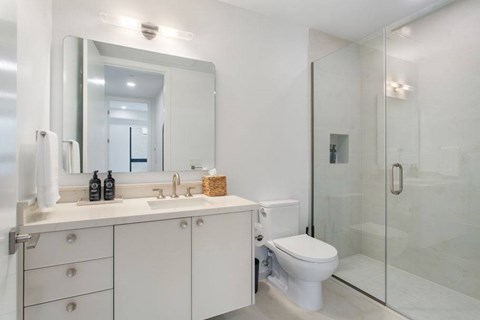 A white bathroom with a toilet, sink, and mirror.