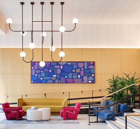 A large abstract painting hangs on a wall above a yellow couch in a modern living room.