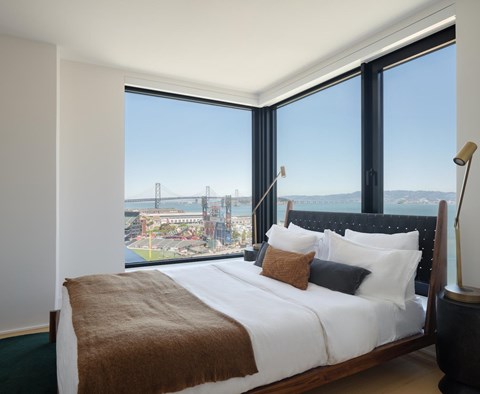 A bedroom with a large bed and a view of a bridge and water.
