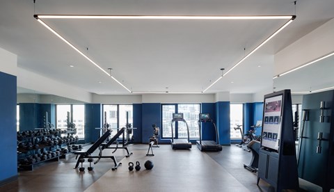 A gym with a variety of equipment including weights, a bench press, and a treadmill.