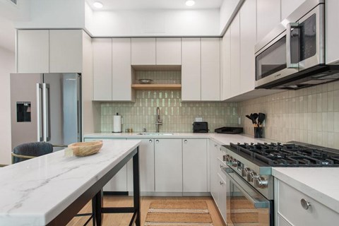 A modern kitchen with white cabinets and a quartz countertop at Ten310