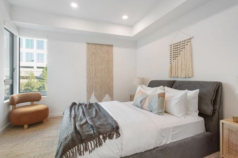 A bedroom with a large bed and a chair by the window at Ten310