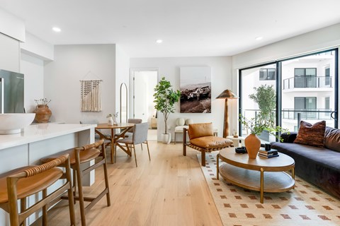A modern living room with a kitchen area in the background.