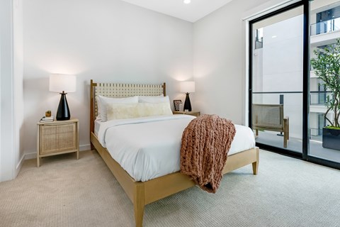 A bedroom with a bed, nightstands, and a window.