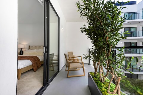 A modern bedroom with a glass door leading to a balcony.