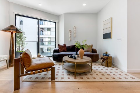 A living room with a brown leather couch, a wooden armchair, and a coffee table.