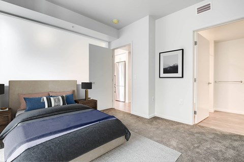A bedroom with a large bed and a framed picture on the wall.