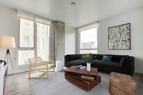 Open living room at Vance in San Francisco, CA.ch, wooden coffee table, and a large window.
