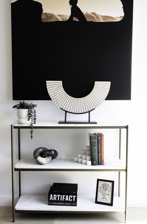 A black and white photograph of a person is displayed on a wall above a shelf with various objects.