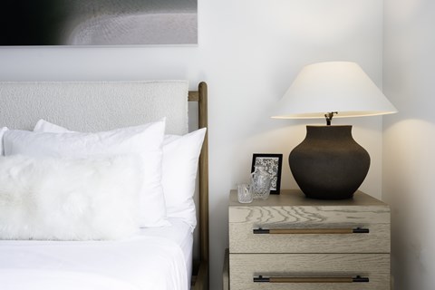 A white bed with a white pillow and a white blanket.