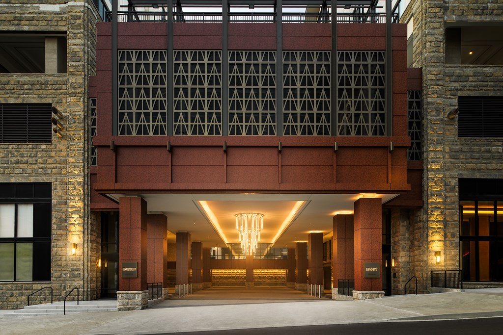 A large building with a red brick facade and a long hallway with a chandelier.
