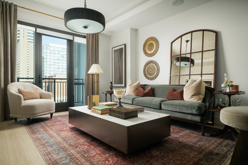 A living room with a large window, a sofa, a chair, a coffee table, and a rug.