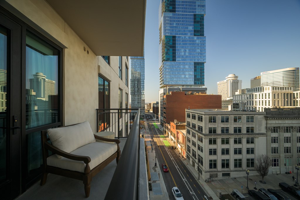 A chair is on a balcony overlooking a city street.