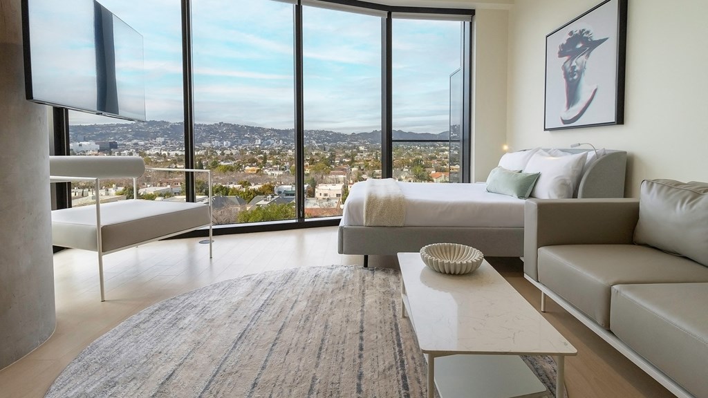 bedroom with a large window and a view of the city Sentral Beverly Hills apartments