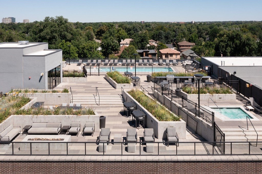 A rooftop pool area with lounge chairs and a view of the city.