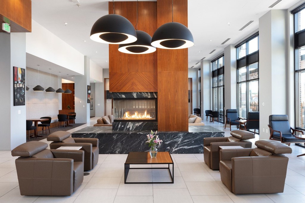 A modern living room with a fireplace and brown leather furniture.