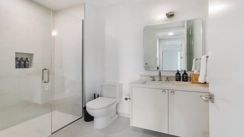 A white bathroom with a toilet, sink, and shower.