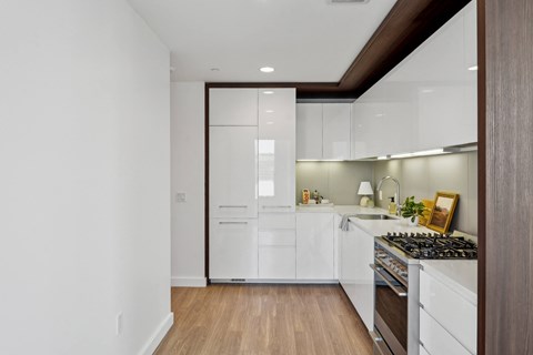 A kitchen with white cabinets and a wooden floor.