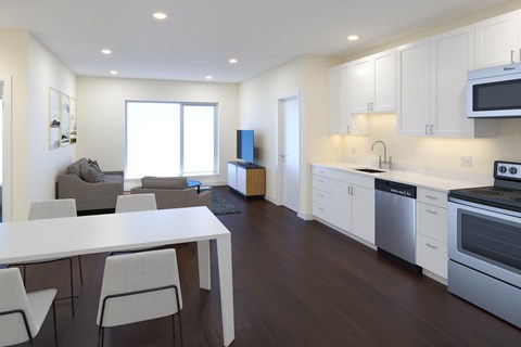 a kitchen and living room with white cabinets and a white table and chairs