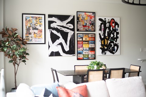 A living room with a white couch and a wall with framed artwork.