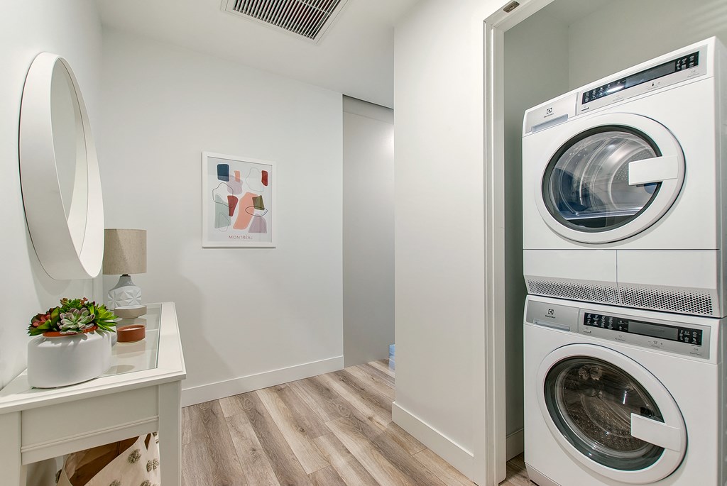 a washer and dryer in a laundry room with a table and a mirror