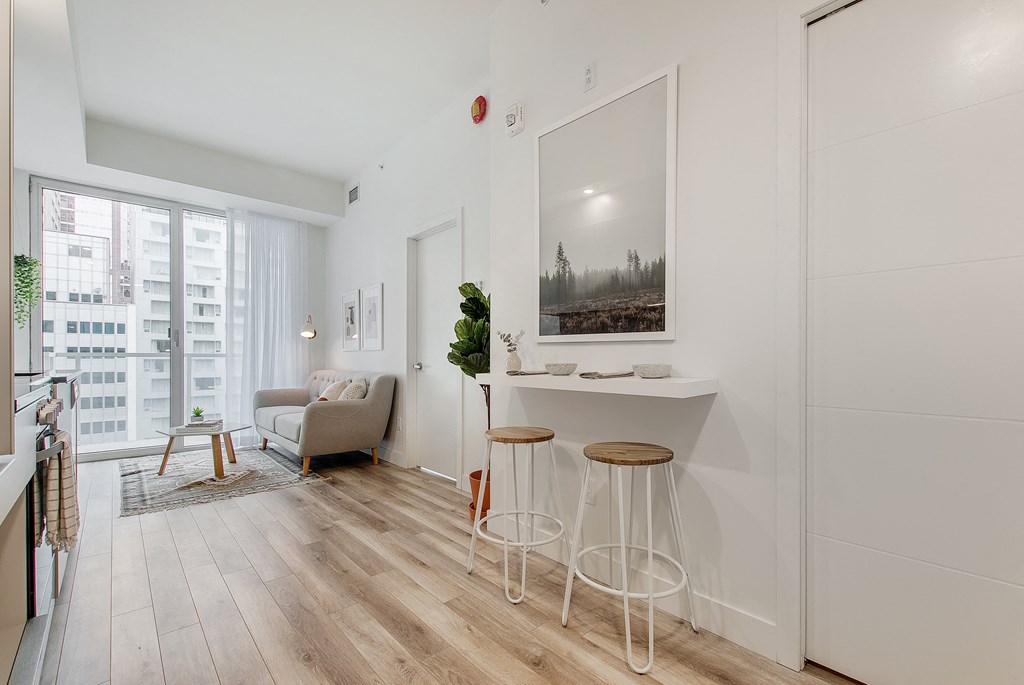 a living room with white walls and a bar with three stools