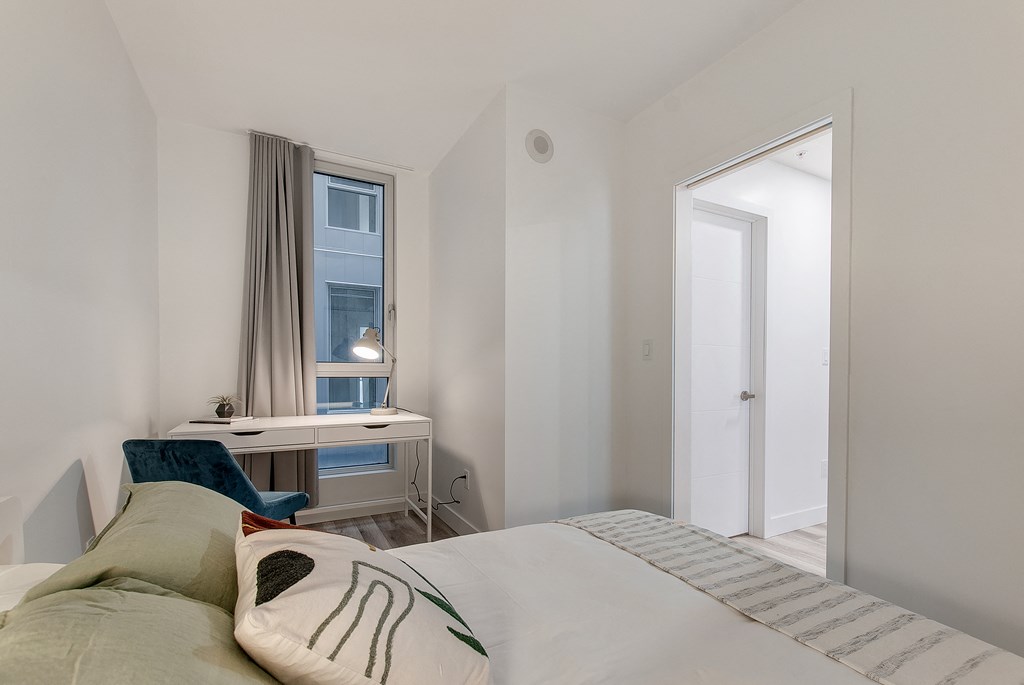 a bedroom with a bed and a desk with a window