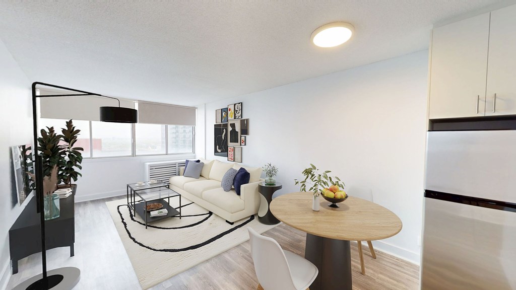 A modern living room with a white sofa, a glass coffee table, and a wooden dining table.