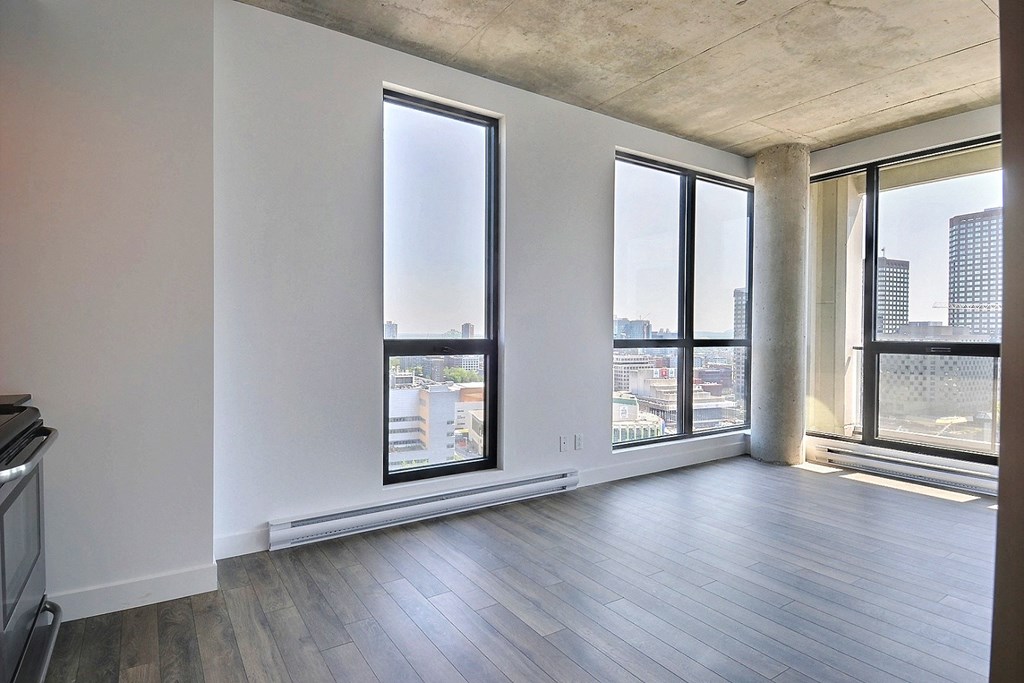an empty living room with large windows and a city view